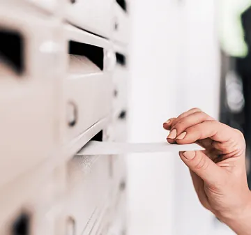 Eine Person wirft einen Brief in den Briefkasten